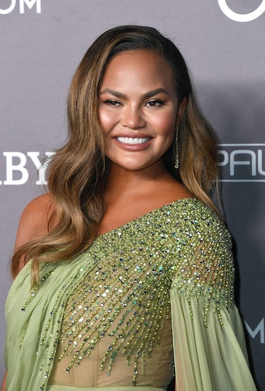 Chrissy Teigen hits the red carpet in a sage green dress.