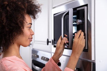 Close-up Of A Smiling Young Woman making a microwave recipe from TikTok in her dorm room.