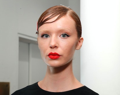 NYFW beauty trends include bold, red lips seen on a  a model who prepares backstage during TRESemme ...
